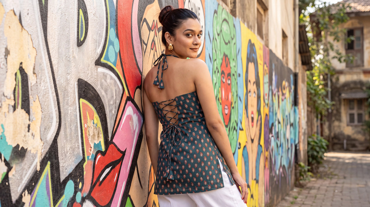 Woman in teal halter lace-up kurti against a Bandra street-art wall
